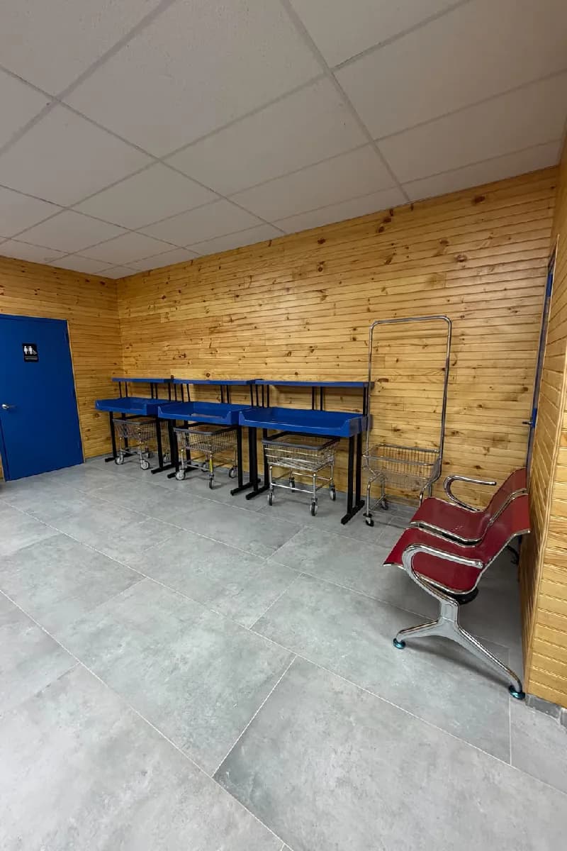 Blue folding tables and red waiting benches in front of the wood-paneled wall